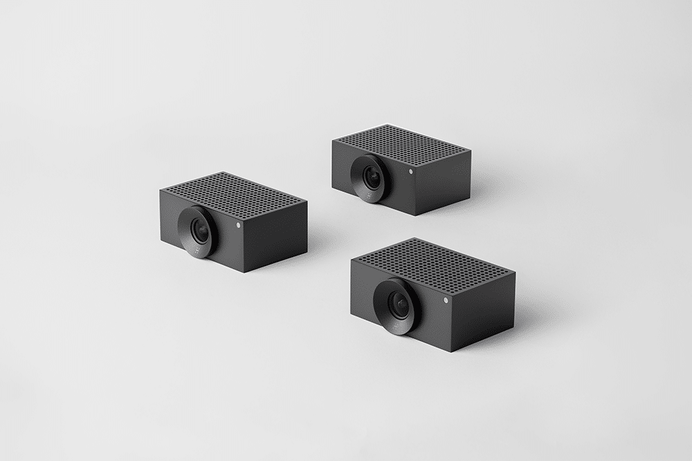 Three black rectangular speakers with circular fronts and grid tops on a white surface.